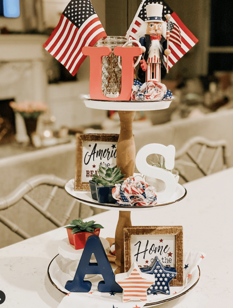 USA letter-themed tray featuring succulents, patriotic scrunchies, a nutcracker, and framed quotes on each tier.
