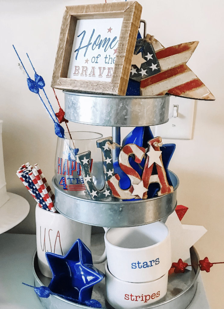 Galvanized tray with wooden 'USA' sign, glitter stars, Happy 4th cup, and a framed 'Home of the Brave' quote.