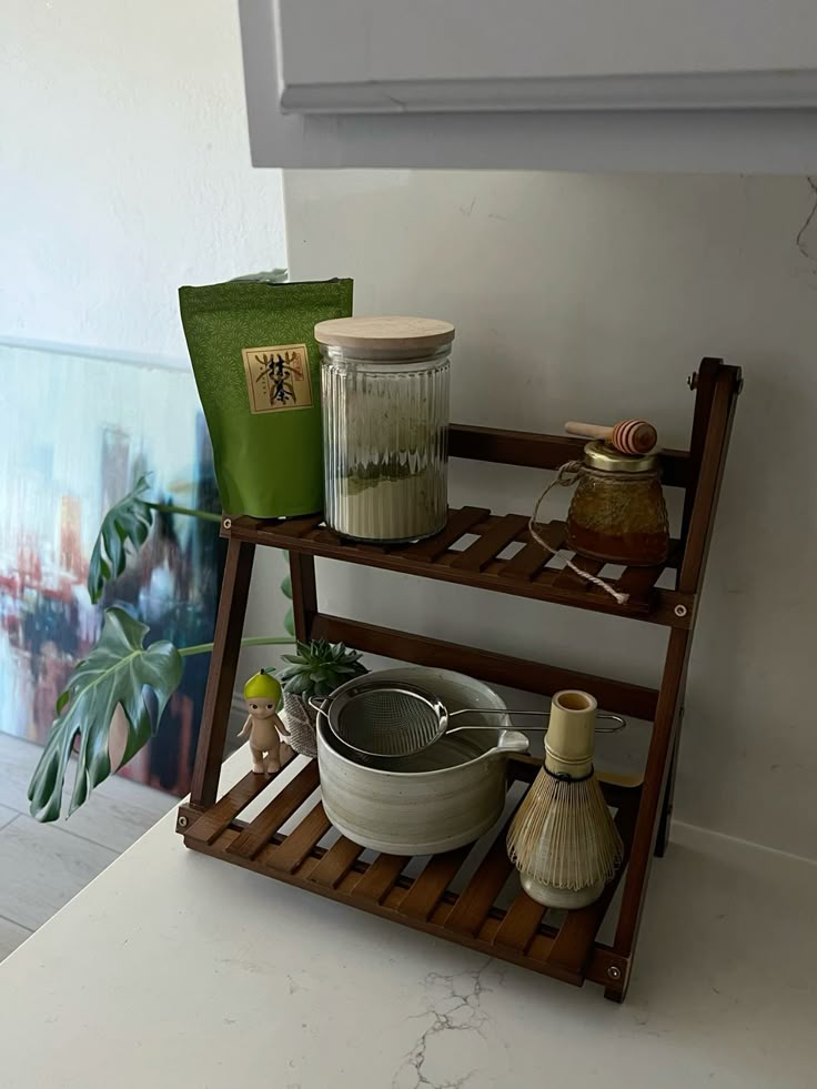 Minimalist wooden matcha shelf with handmade ceramic bowl, honey jar, and matcha powder in a jar.