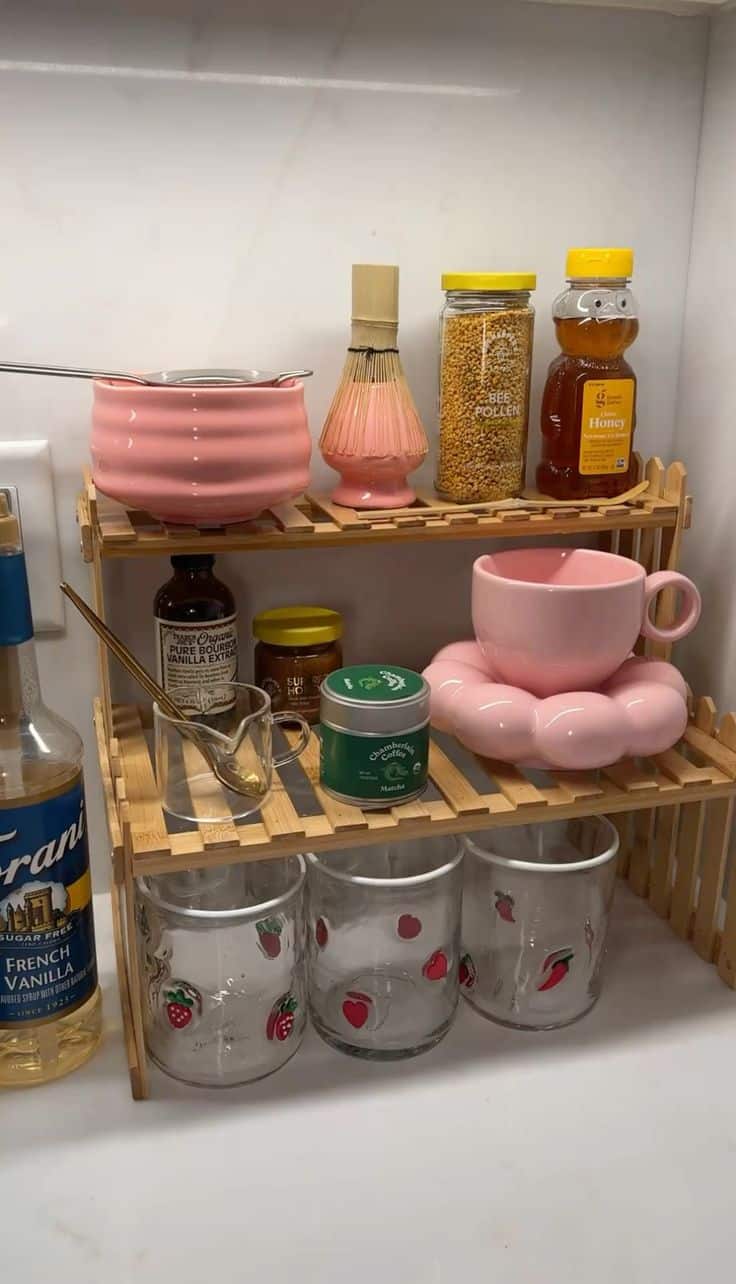 Pink-themed matcha setup with bee pollen, honey, and playful glass jars on a bamboo shelf.