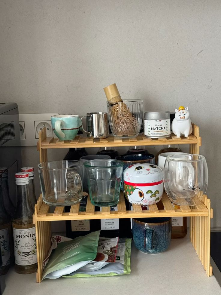Clear mug collection and matcha tools arranged on a two-tier bamboo shelf with cute accessories.