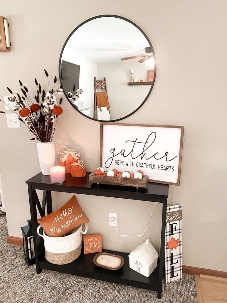 Modern farmhouse entryway decorated with pumpkins, cotton stems, and a ‘gather’ sign under a round mirror