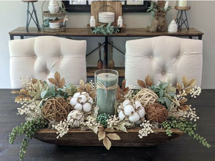 Fall dough bowl centerpiece with a sage green candle, cotton, rattan spheres, white pumpkins, and trailing greenery.