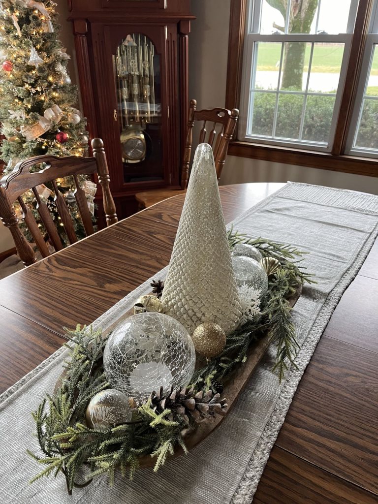 Christmas dough bowl centerpiece with a conical gold tree, crackle glass ornaments, and pine garland.