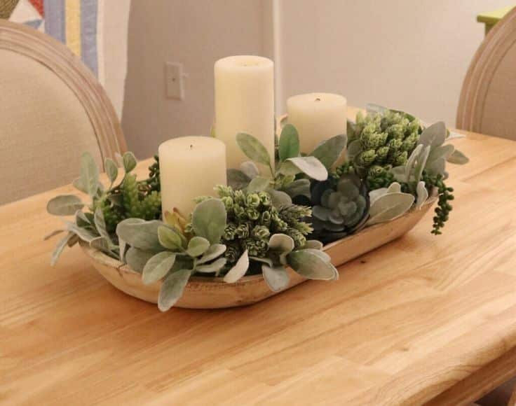 Light wooden dough bowl centerpiece with three cream candles, lambs ear, and mixed faux succulents.