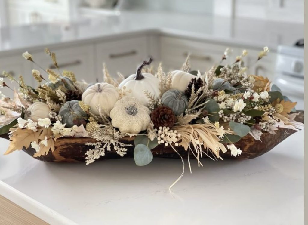 Abundant farmhouse fall dough bowl centerpiece with neutral dried florals, eucalyptus, and white/blue pumpkins.