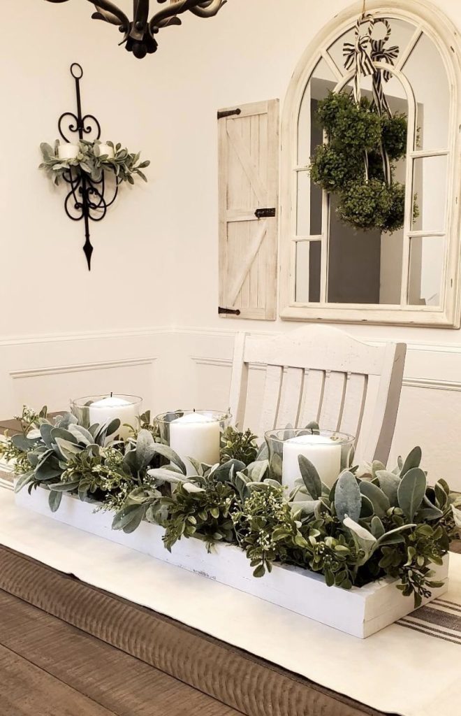 Long white farmhouse planter centerpiece with white pillar candles, lamb's ear and sage green garland.