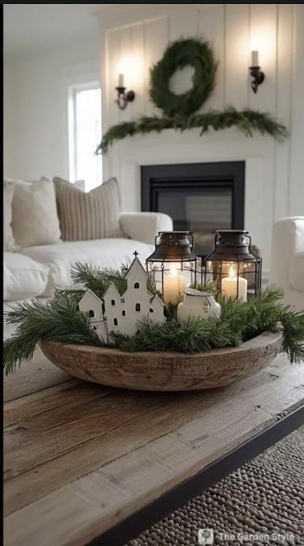 Rustic Christmas dough bowl centerpiece with tiny white village houses, lanterns, and pine garland.