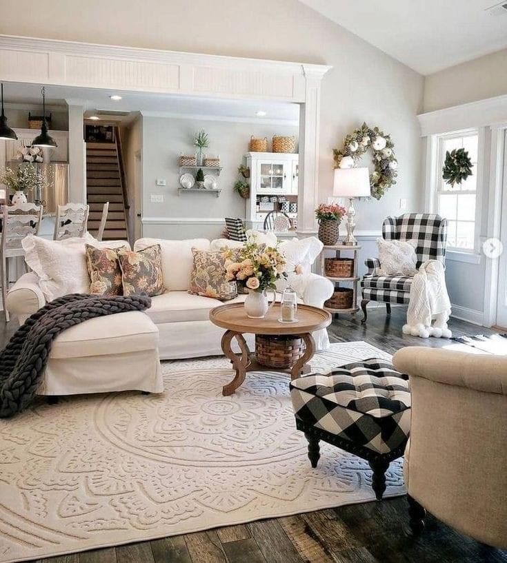 Farmhouse living room with white sofa, check buffalo plaid accent chair and ottoman, and round wood coffee table on a patterned rug.