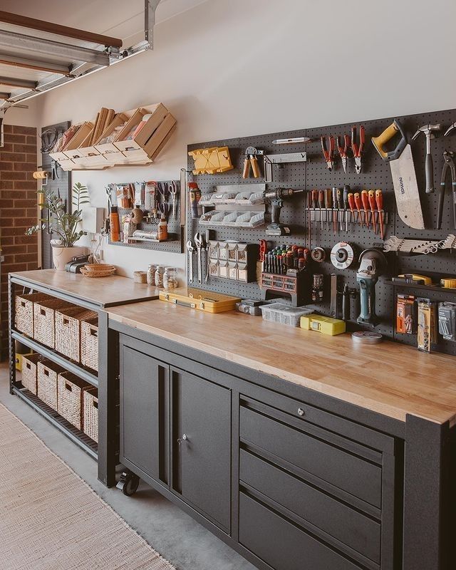 Close up of a professional dark gray workbench with wooden top, pegboard for tools, and baskets on the lower shelf.