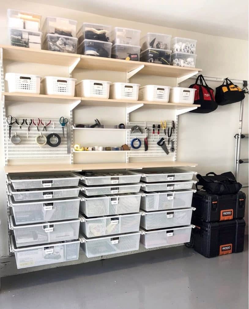 Custom white and natural wood wall-mounted shelving system with wire pull-out drawers and a perforated metal pegboard section for small tools.