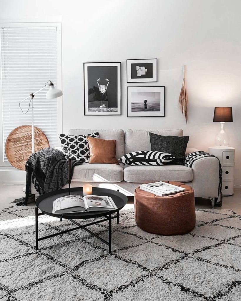 Three black-and-white photography prints in black frames arranged in a line above a grey sofa.