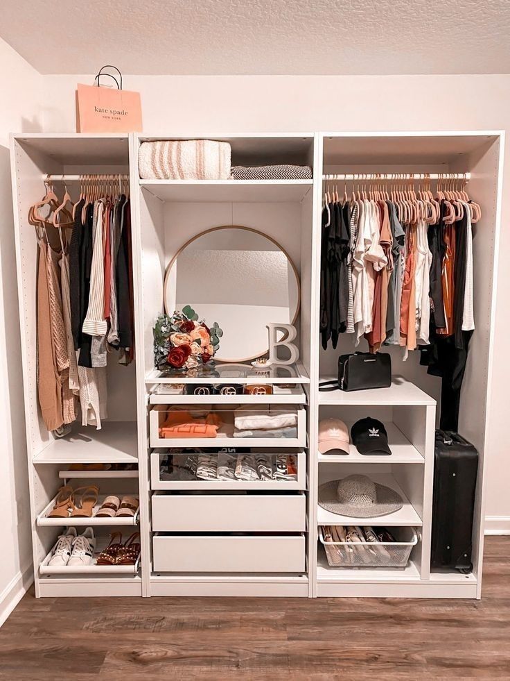 Custom white wardrobe system with gold hardware, central mirror, shoe storage, and blush velvet hangers.