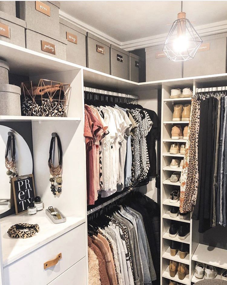 Glamorous corner walk-in closet with double hanging rods, shoe shelves, labelled gray storage boxes, and mirrored accessory display area.