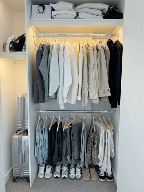 Double hanging closet rods with neutral, gray, and white clothing organized by color, with sneakers lined up on the floor below.