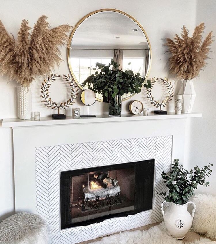 White fireplace mantel with round gold mirror, tall pampas grass arrangements, eucalyptus greenery, and gold wreath decor accents