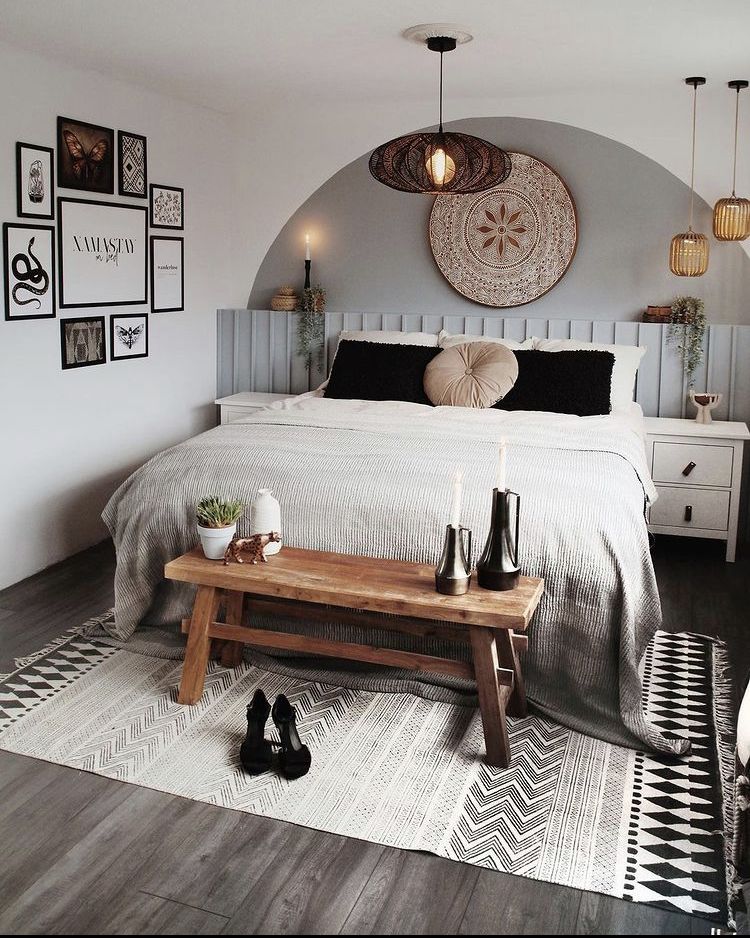 Boho bedroom with an arched grey paint feature on the wall above the bed, decorated with a large woven wall plate, wicker pendant lights, and a gallery wall of framed prints on the adjacent wall.