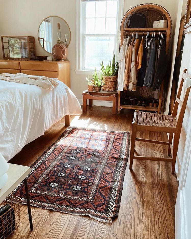 Small boho bedroom with a vintage Persian-style rug, rattan wardrobe, and wooden furniture