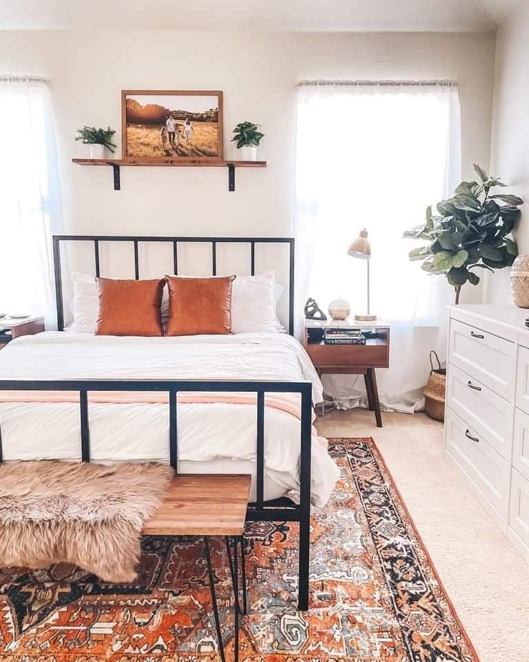 Boho bedroom with a floating shelf above the bed styled with a framed photo, plants, and warm lighting