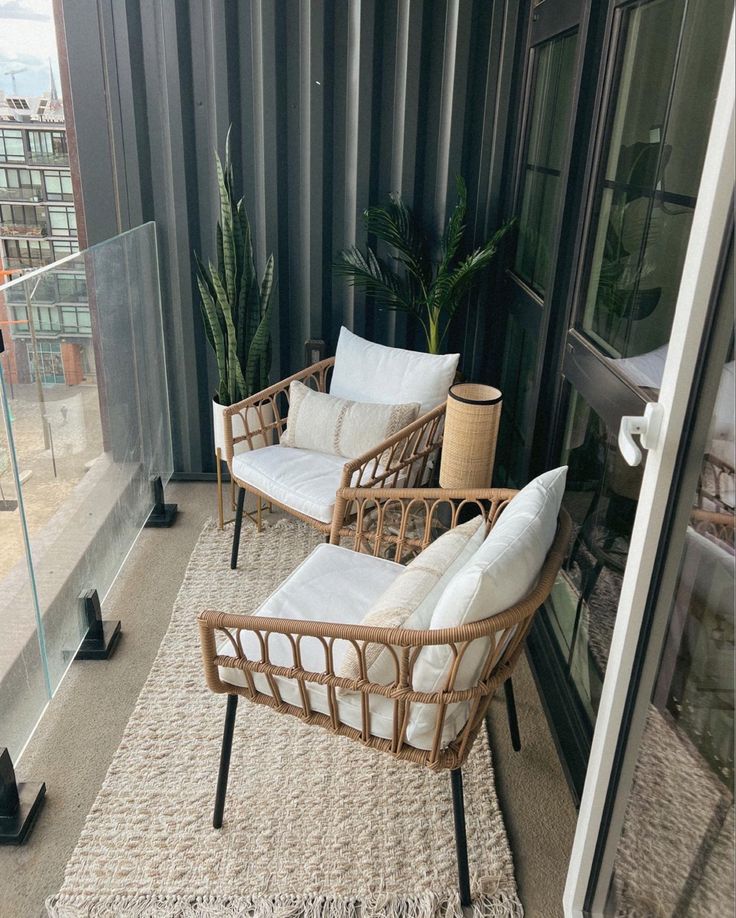 Small balcony decor with rattan chairs, white cushions, jute rug and tall plants