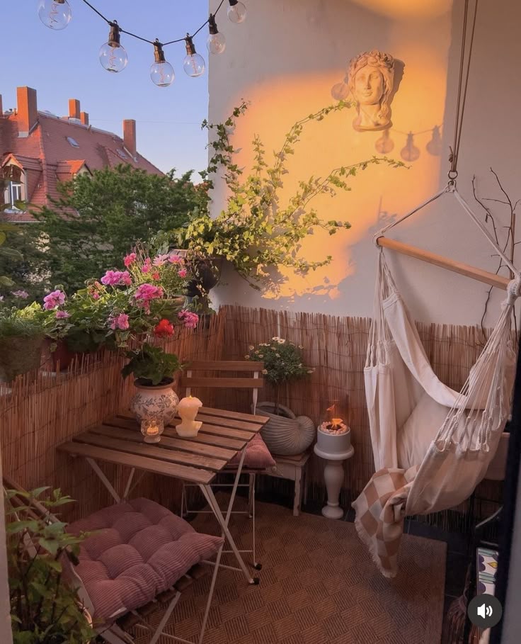 Romantic small balcony at dusk with hammock chair, festoon lights, candles, trailing ivy and geraniums