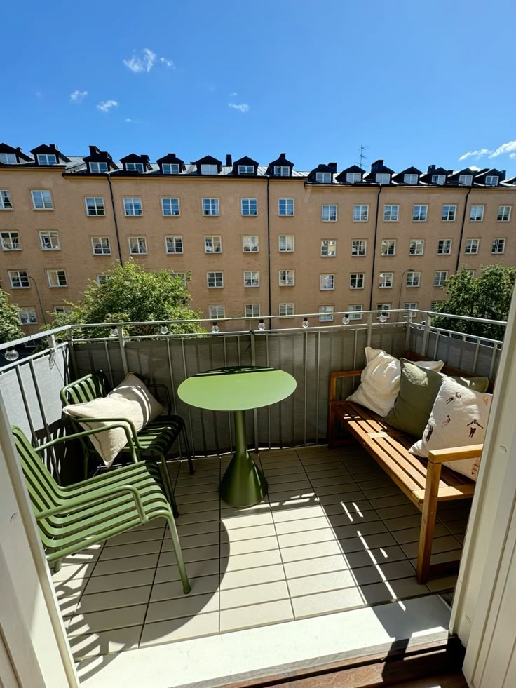 Bright modern small balcony with sage green metal chairs, matching round table, wood bench with cushions
Image 19: Cozy small balcony at ni