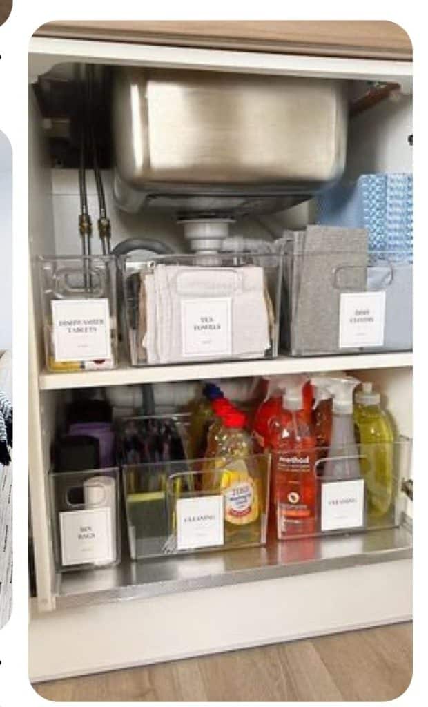 Under kitchen sink cabinet showing two shelves of clear acrylic storage bins with printed white labels for dishwasher tablets, tea towels, toilet cleaner, bin bags and cleaning products