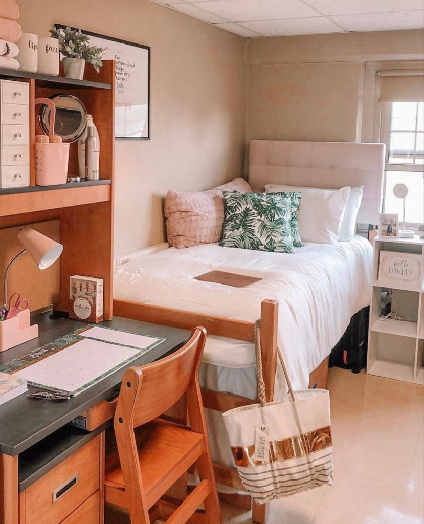Pink dorm room desk with a hutch shelf, pink accessories, and a compact mirror