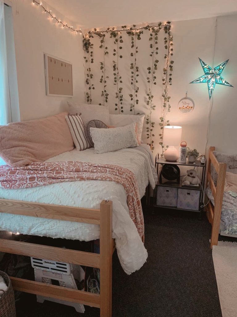 Pink dorm room with trailing faux ivy on the wall and a glowing star lamp