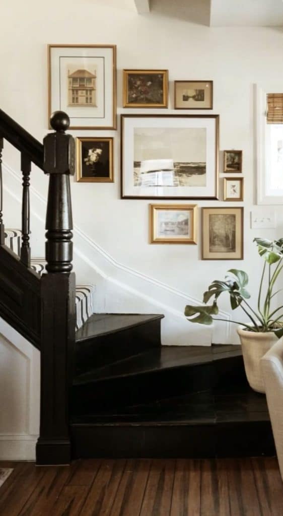 Gold framed landscape art gallery wall on staircase with potted plant
