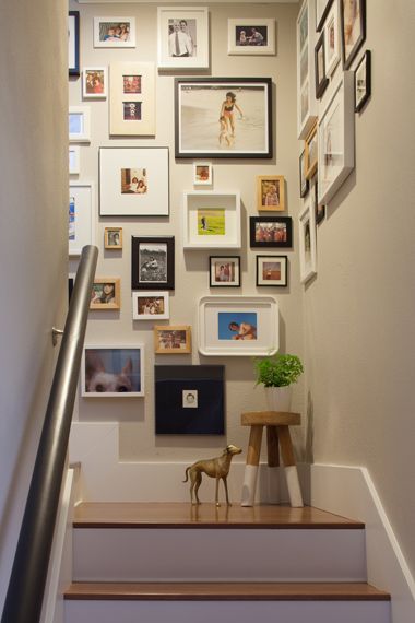 Densely packed eclectic gallery wall on staircase with decorative figurine on steps