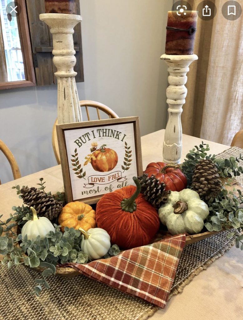 Cozy fall dough bowl with a love fall most of all sign, mixed white, green, and orange pumpkins, pinecones, eucalyptus, and tall distressed candlesticks.