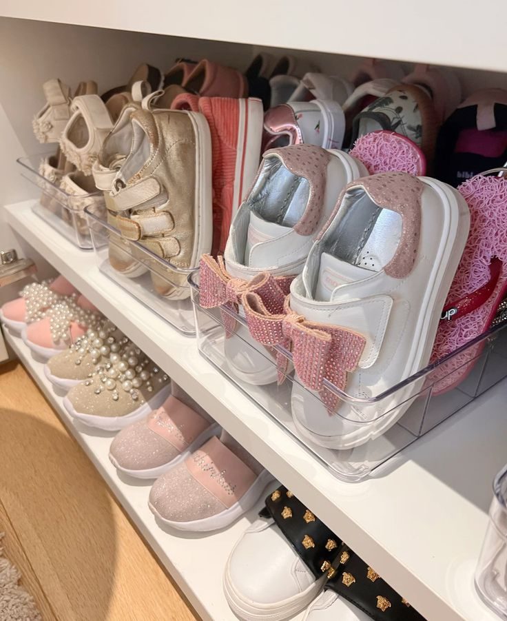 Clear plastic bins holding kids shoes on a closet shelf