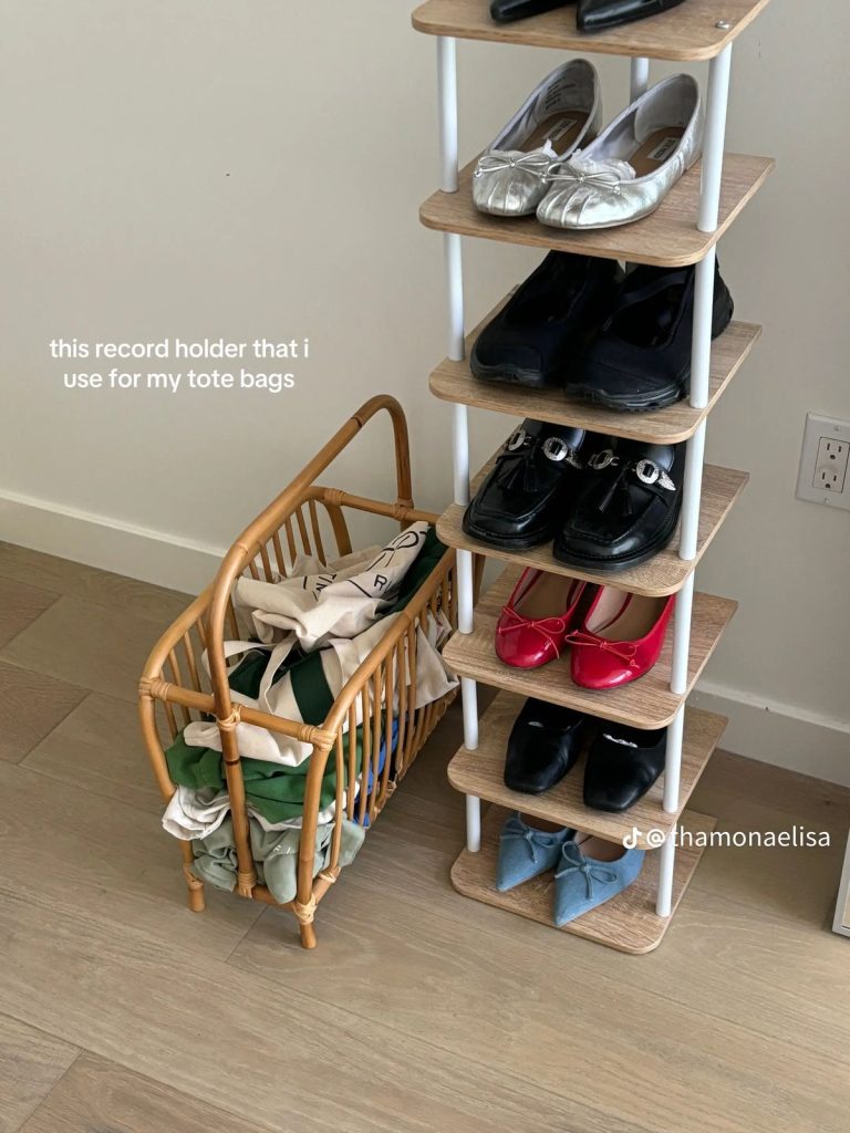 Narrow wooden and white shoe tower holding one pair per shelf, next to a rattan basket filled with folded tote bags.