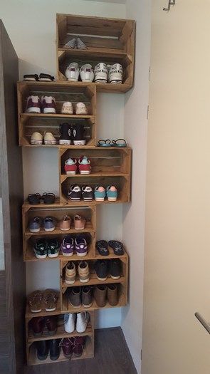 Wooden crates mounted in a staggered arrangement on a narrow wall, each one holding two rows of sneakers and flats.