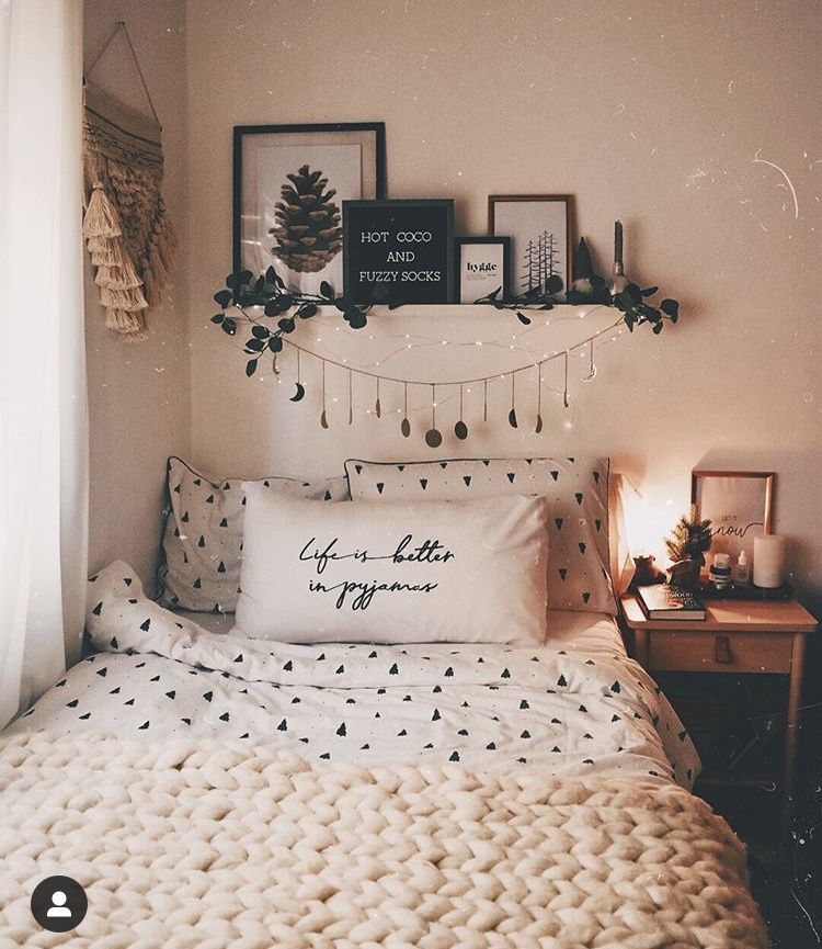 A floating shelf displays a framed pinecone print and a Hot Coco and Fuzzy Socks sign above a bed with tree print bedding.