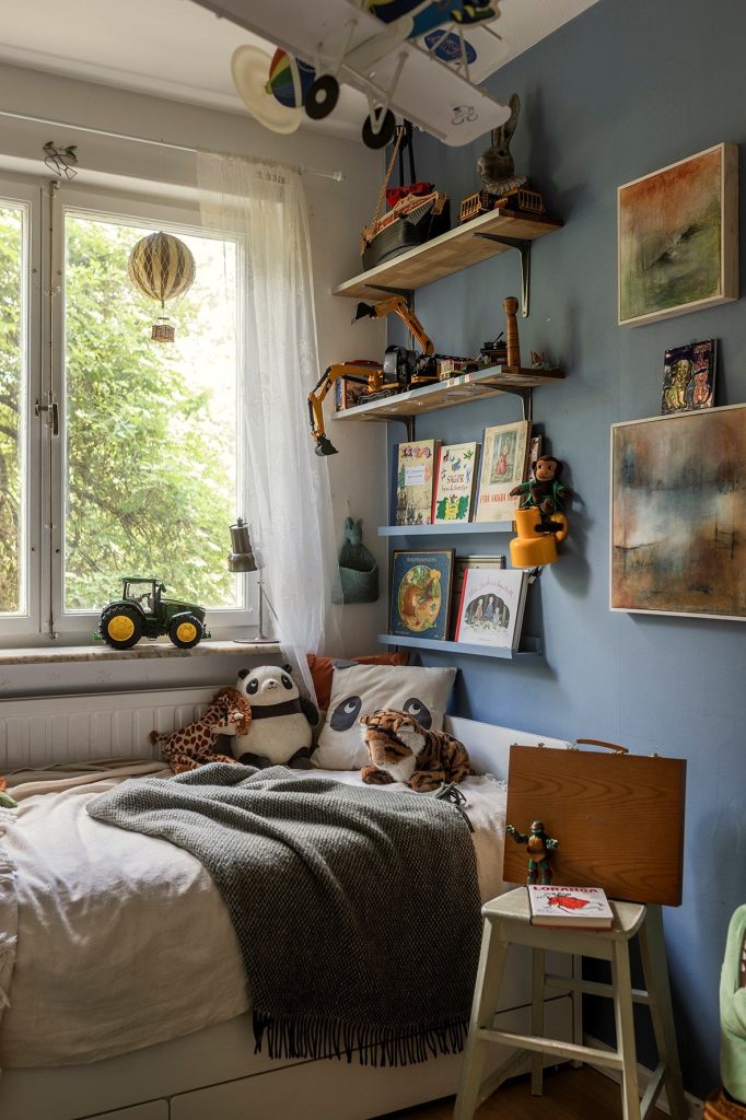 Blue kids bedroom with corner wall shelves and hanging toy plane