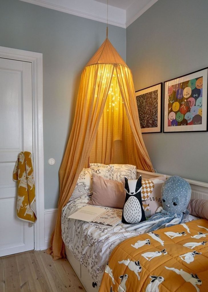 Small kids bedroom with mustard canopy over a corner bed