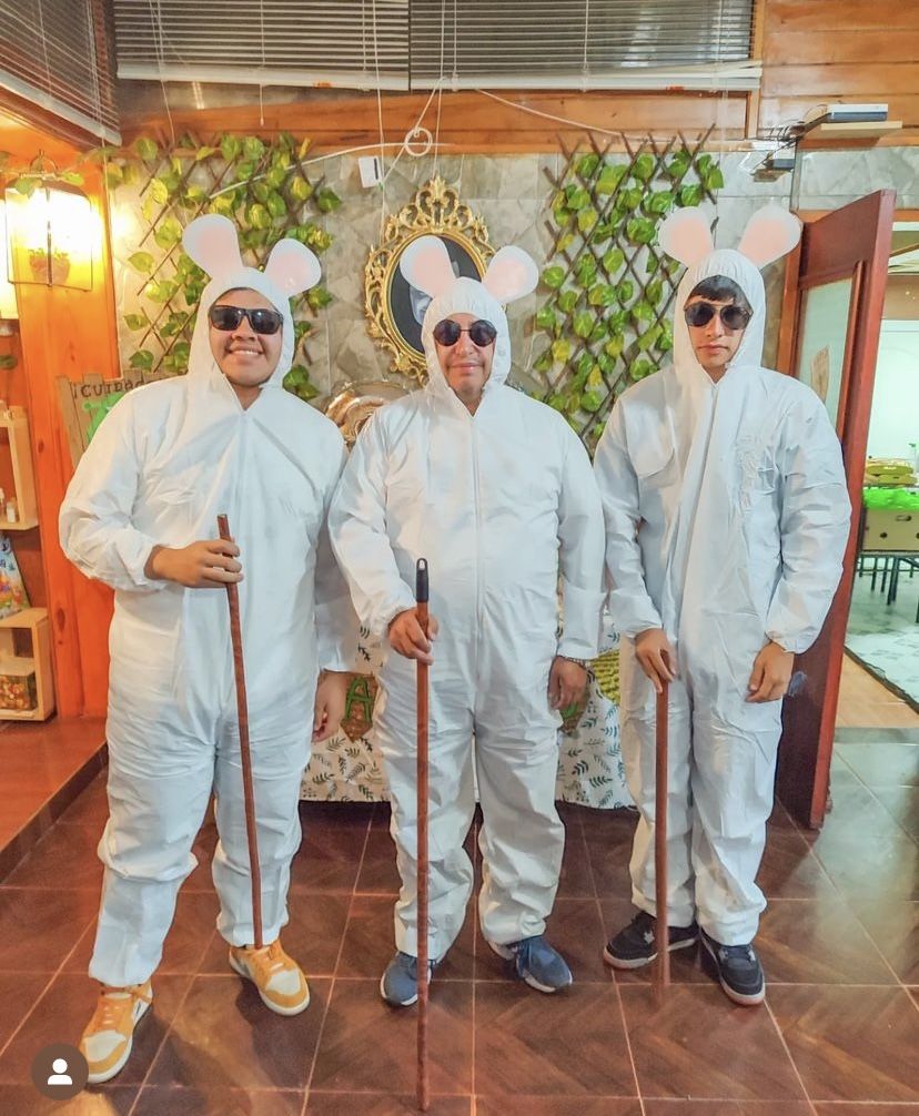 Three people dressed as the three blind mice in white boiler suits with round mouse-ear headbands, dark sunglasses and walking canes.