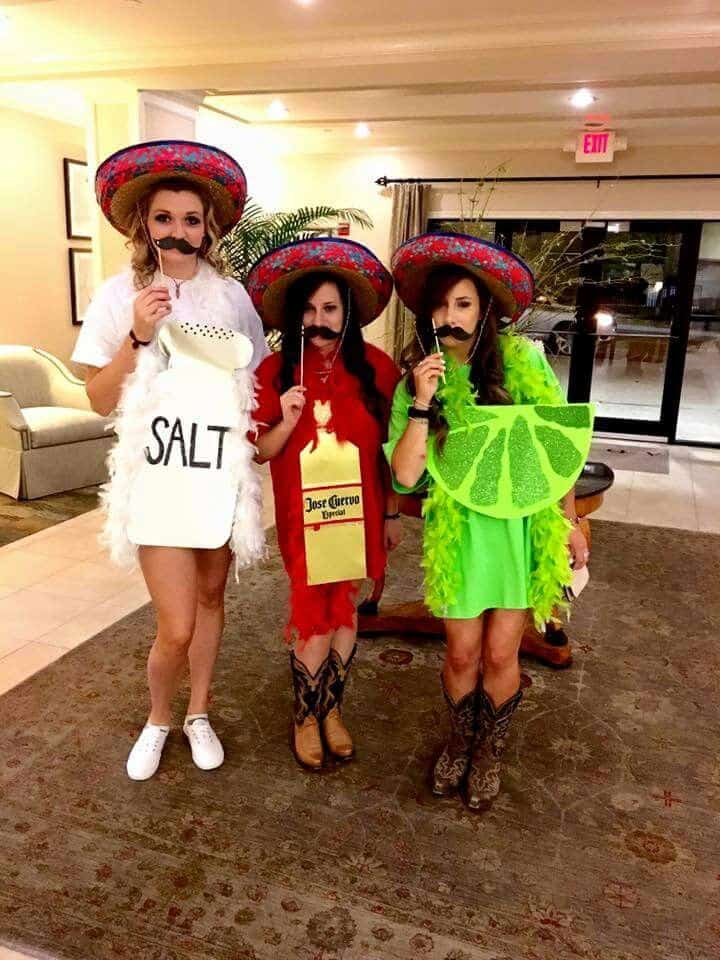 Three people dressed as salt, a tequila bottle and a lime slice, wearing sombreros, feather boas and stick-on mustaches.